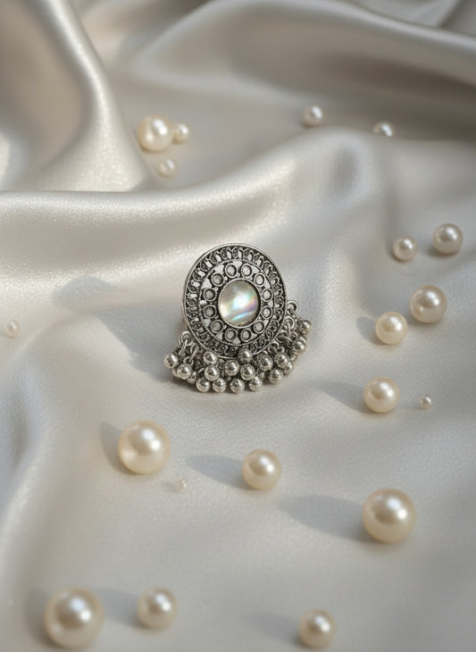 Silver ring with decorative elements on a white textured surface