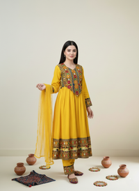 Woman wearing a yellow embroidered traditional outfit with a plain background