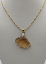 Gold necklace with a brown pendant on a gray background