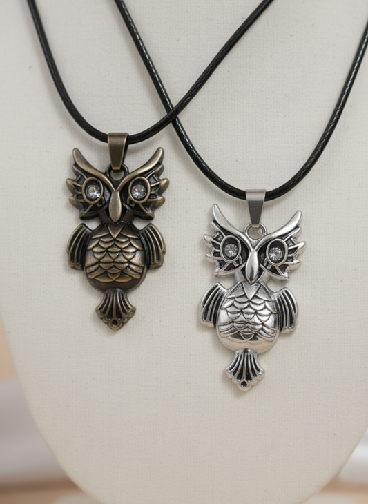 Two owl-shaped pendants on black cords against a white background