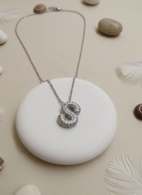 Silver necklace with a unique pendant on a white stone surrounded by small stones and shells.