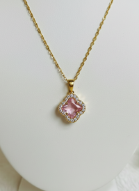 Gold necklace with a green gemstone pendant on a white background