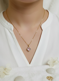 Gold necklace with a green pendant on a neutral background