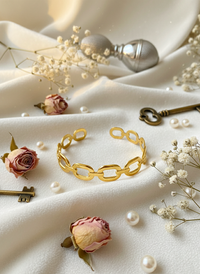 Gold bracelet with flowers and keys on a white fabric background