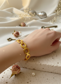 Gold chain bracelet on a wrist with a soft focus background