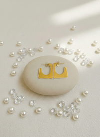 Gold hoop earrings on a stone with scattered pearls and crystals