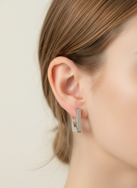 Silver hoop earrings worn by a person with a neutral background