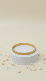 White jar with a gold lid on a beige background with scattered pearls