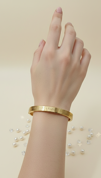 Gold bracelet on a hand with a beige background
