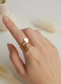 Hand wearing gold rings with a blurred background