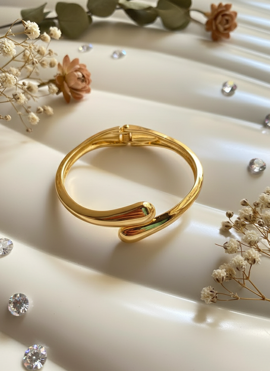 Gold bracelet on a white surface with decorative elements