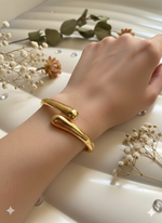 Gold bracelet on a wrist with dried flowers in the background