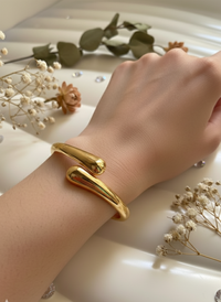 Gold bracelet on a wrist with dried flowers in the background