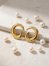 Gold hoop earrings with pearls on a light background