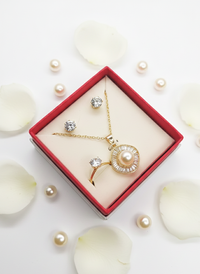 Gold necklace with a pearl pendant in a red box surrounded by white petals and pearls.