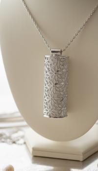 Silver lace-patterned pendant on a chain against a neutral background