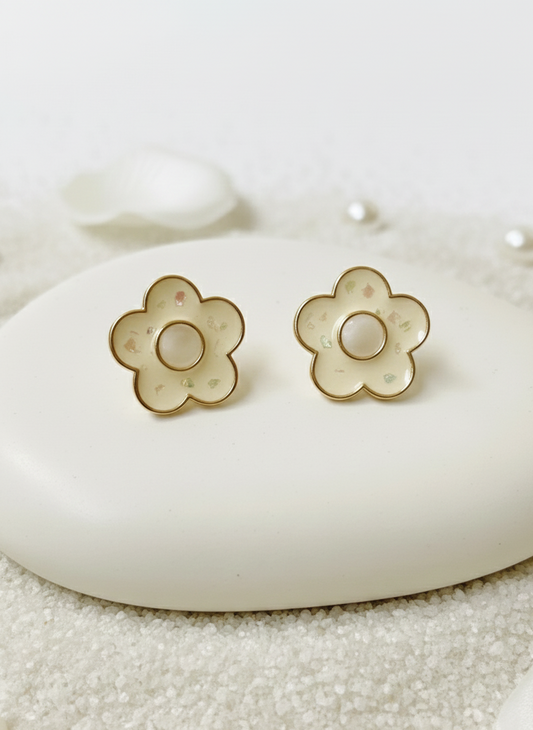 Flower-shaped earrings on a white stone surface