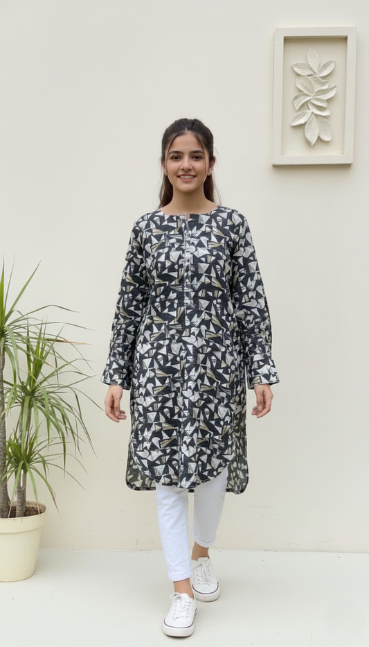 Woman wearing a patterned kurta with white pants standing against a light-colored wall.