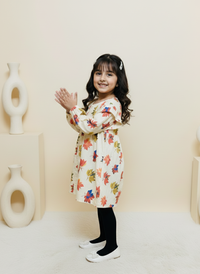 Young girl in a floral dress standing against a plain background