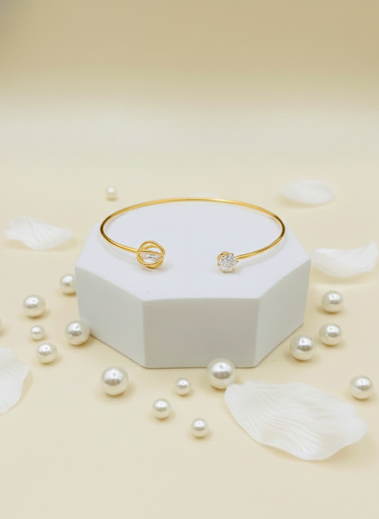 Gold bracelet with pearls on a white hexagonal stand and scattered pearls on a beige background