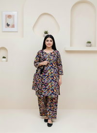 Woman wearing a colorful outfit standing against a white wall with decorative elements.