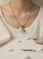 Necklace with a pendant on a mannequin wearing a cream sweater.