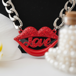 Necklace with red lips and 'love' pendant on a black background