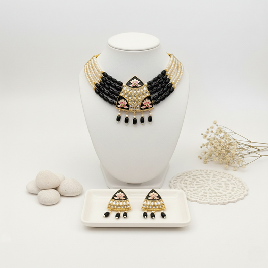Black and gold necklace and earrings on a white stand with a white background