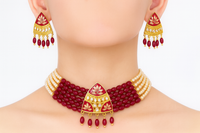 Red and gold necklace with matching earrings on a neutral background