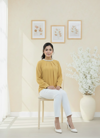 Woman sitting on a chair in a room with light-colored walls and decorative elements.
