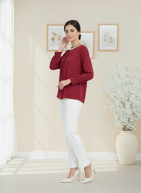 Woman wearing a red blouse and white pants in a room with decorative elements.