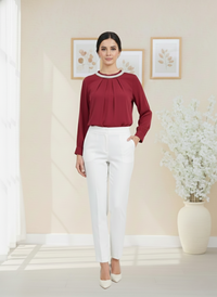 Woman wearing a red blouse and white pants in a room with decorative elements.