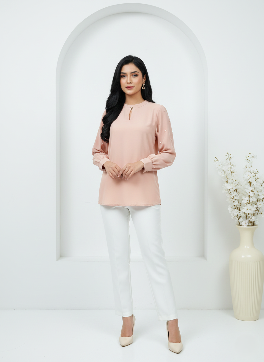 Woman wearing a pink top and white pants standing in front of a white archway.