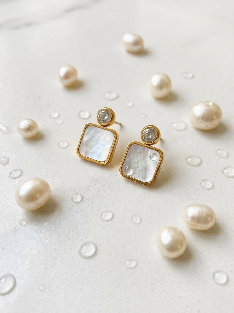 Gold earrings with square母贝片 surrounded by pearls on a light background