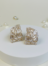 Pair of silver beaded earrings on a white platform with pearls around.