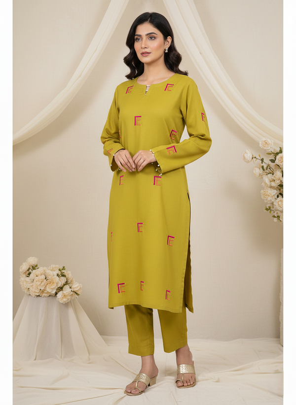 Woman wearing a green kurta with red patterns against a white curtain background