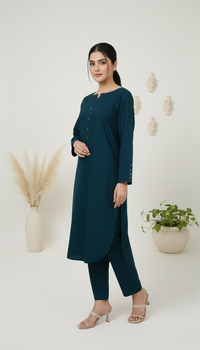 Woman wearing a teal outfit standing in a minimalistic room with plants.