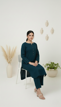 Woman in teal outfit sitting on a white chair with decorative plants in the background