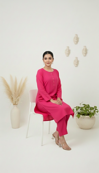 Woman in a pink outfit sitting on a white chair with decorative elements in the background