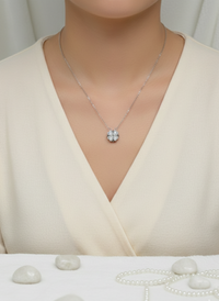 Necklace with a star-shaped pendant on a mannequin wearing a beige dress, with pearls on a white background.