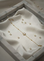 Pearl necklace with gold chain on a white marble surface