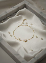 Gold necklace with pearls on a white marble surface