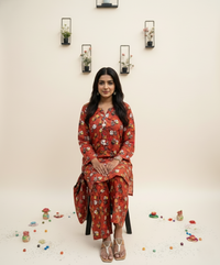 Woman in a red floral traditional outfit standing against a light background with decorative elements.