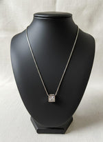 Necklace with a square pendant on a black mannequin bust against a light background