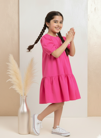 Young girl in a pink dress standing against a neutral background with decorative elements.