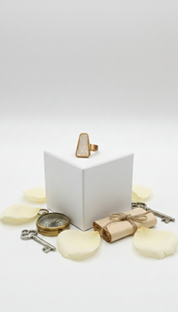 Gold ring on a white box with decorative items on a light gray background