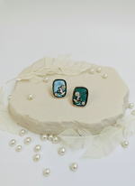 Purple earrings with a star design on a white stone surrounded by pearls