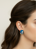 Close-up of a woman wearing a blue and gold earring with a neutral background