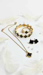 Gold and black jewelry set including necklace, ring, and earrings on a white background