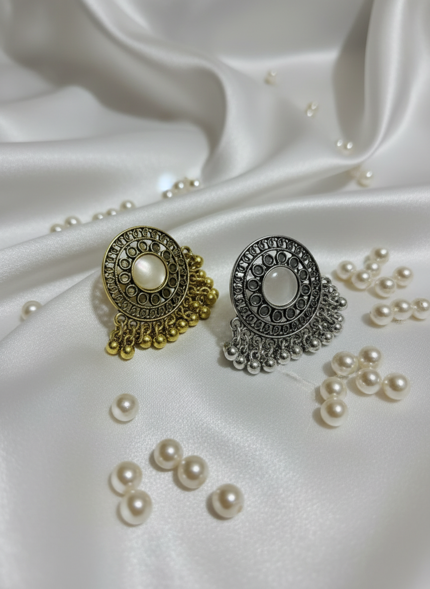 Two pairs of earrings, one gold and one silver, on a white satin background.